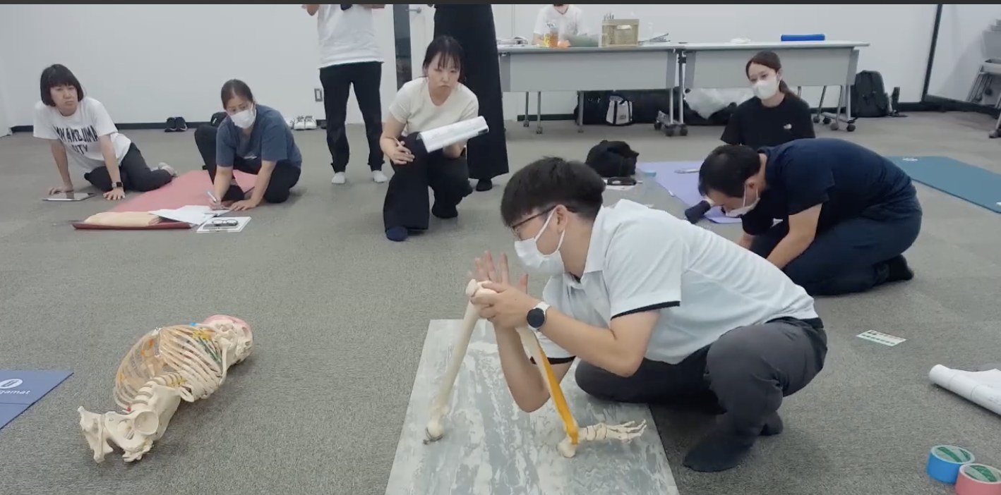 骨模型の下肢を手に持ち、形と向きを確かめている様子