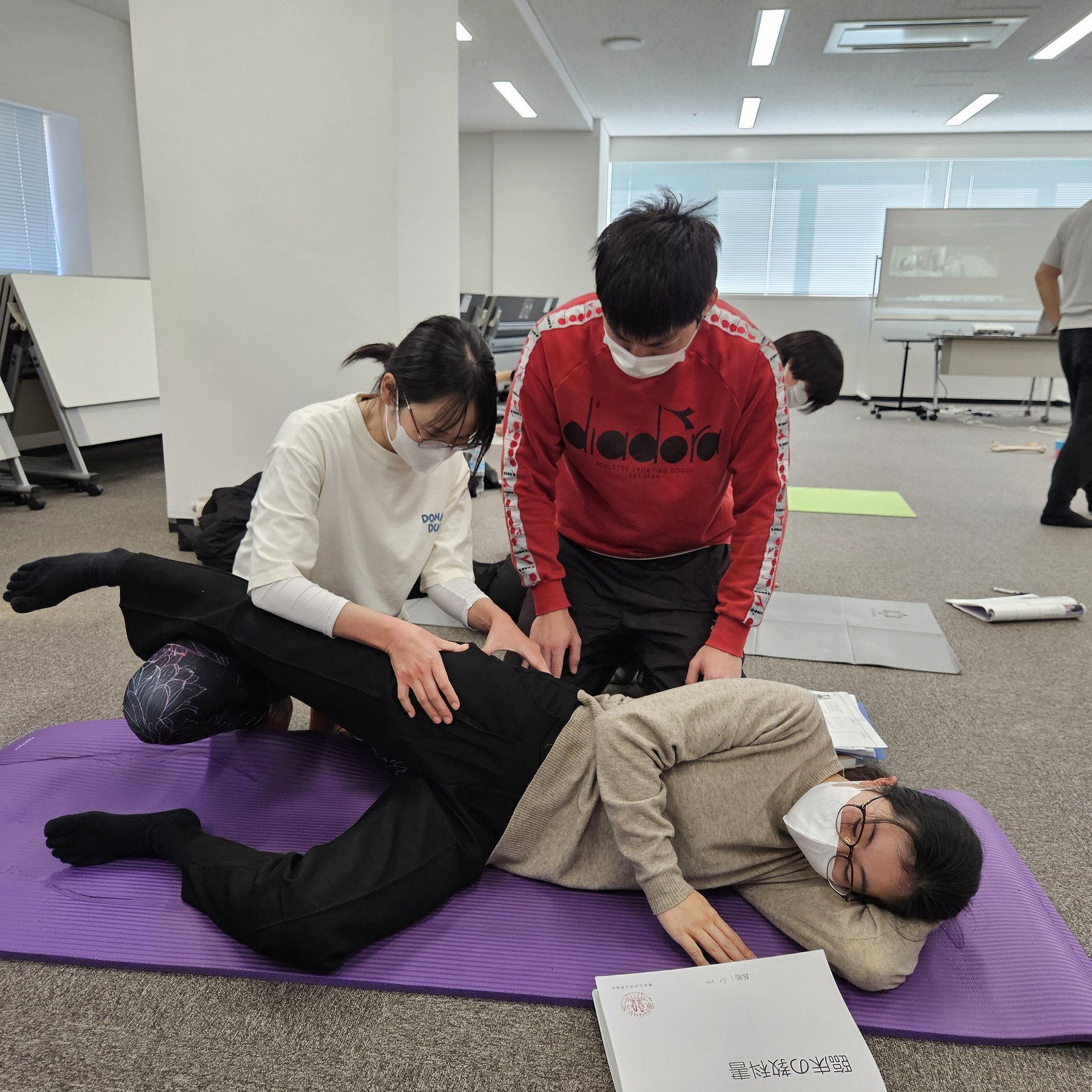 側臥位の受講生の体幹に二人で触れている実技の様子