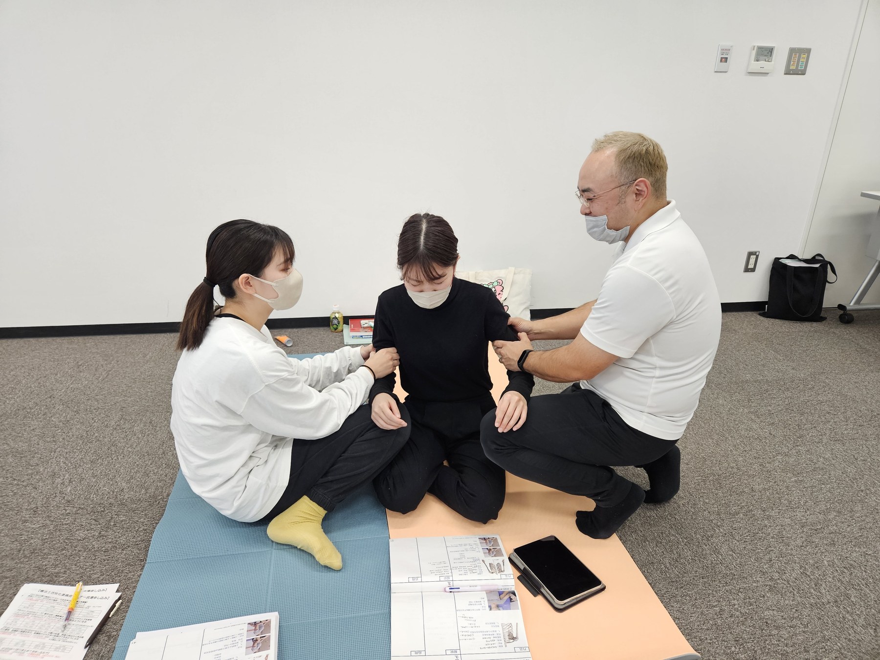 座位の受講生の体幹に両側から触れ、講師が確認している様子
