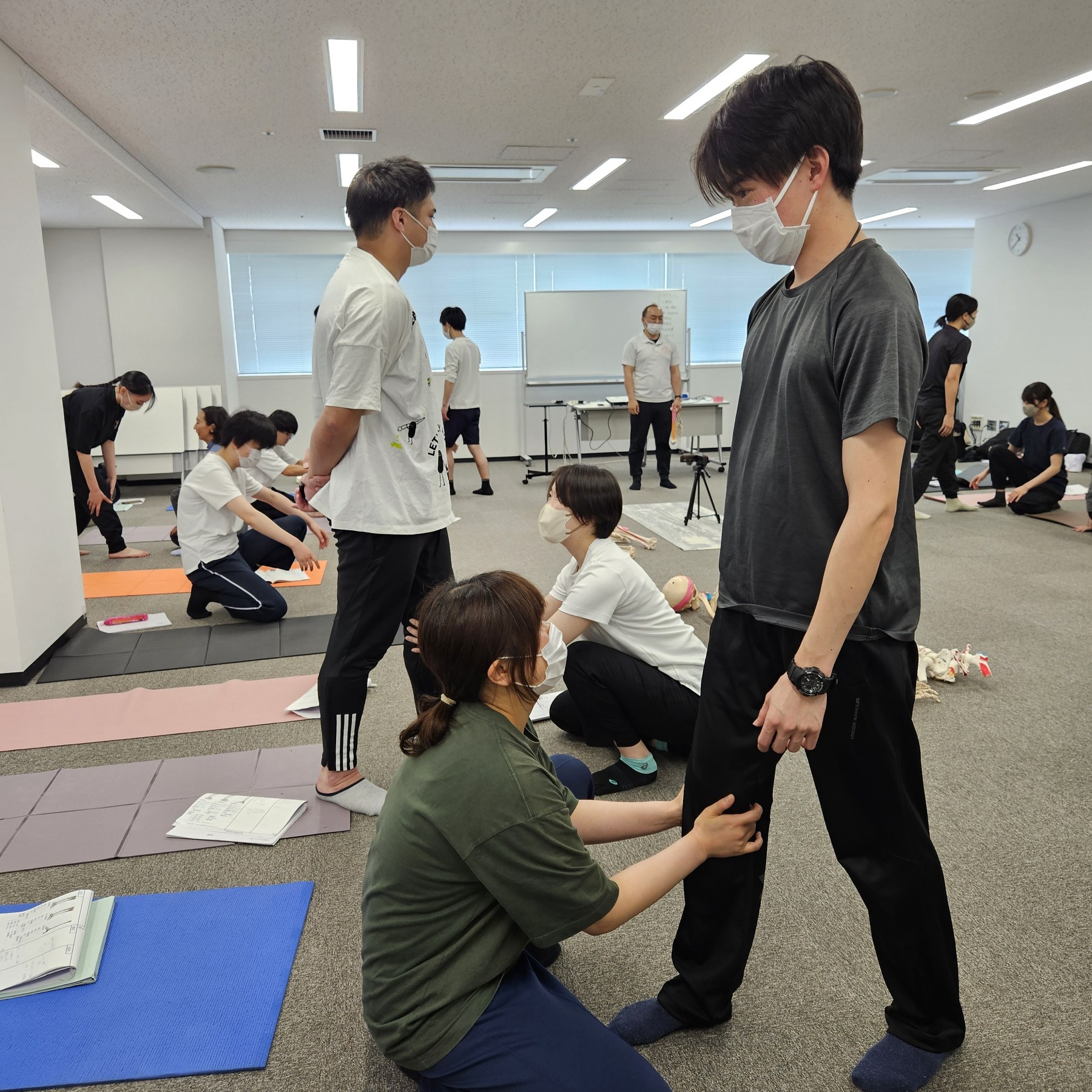 立位の受講生の下肢に触れ、動きを確かめている様子